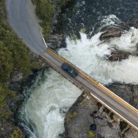 Drone photo of a truck driving over a bridge with a river below.