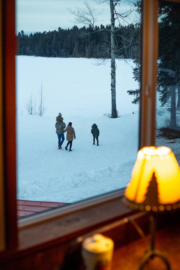 Family walking in the snow outside a window at Ruth Lake Lodge Resort.
