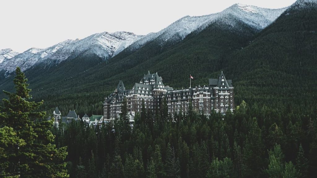 The Banff Springs Hotel surrounded by trees and snow-capped mountains